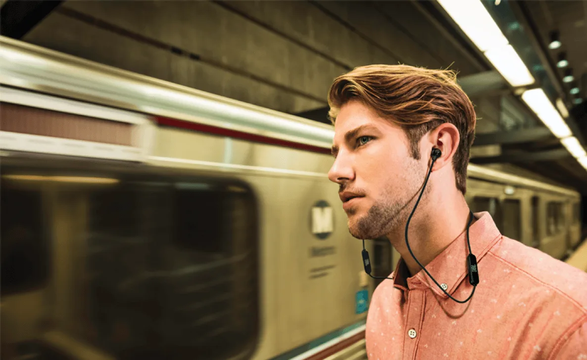 Fones de ouvido bluetooth preto sobre uma mesa de madeira com smartphone.